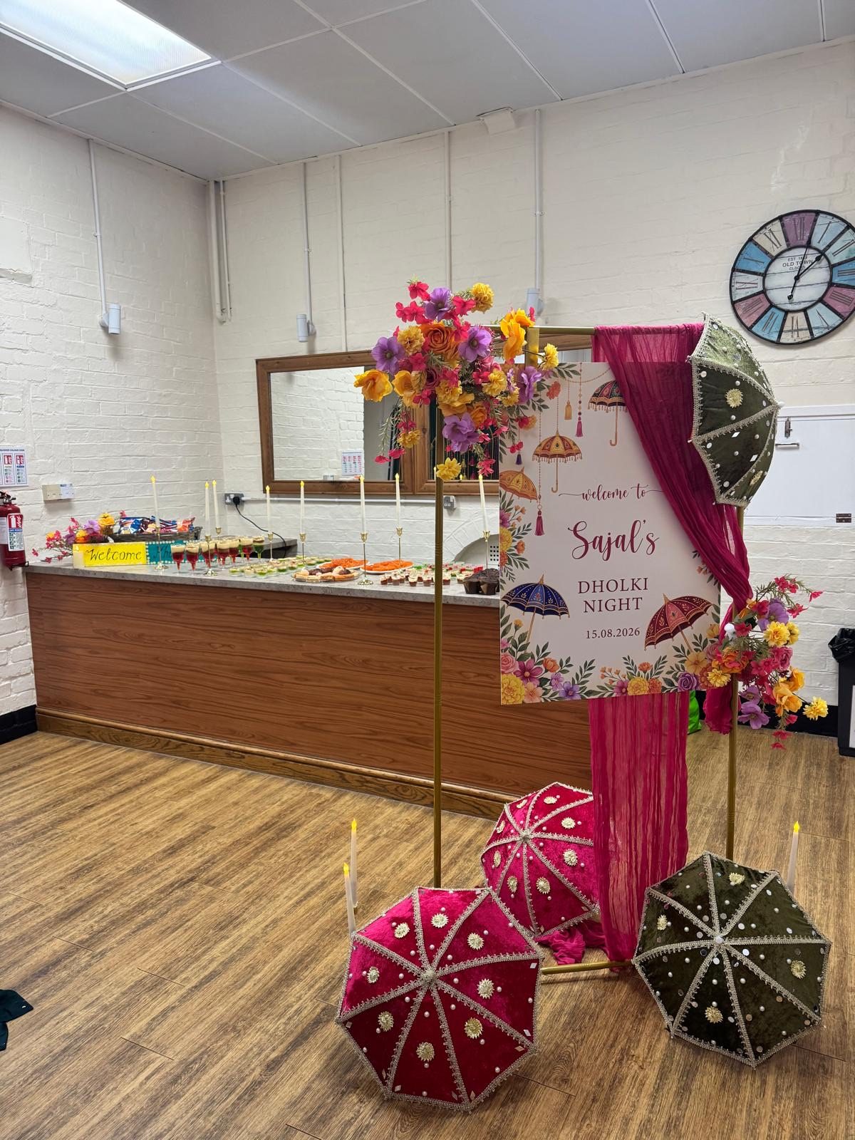 Dholki night welcome display with hand-painted umbrellas, vivid florals and a dessert table