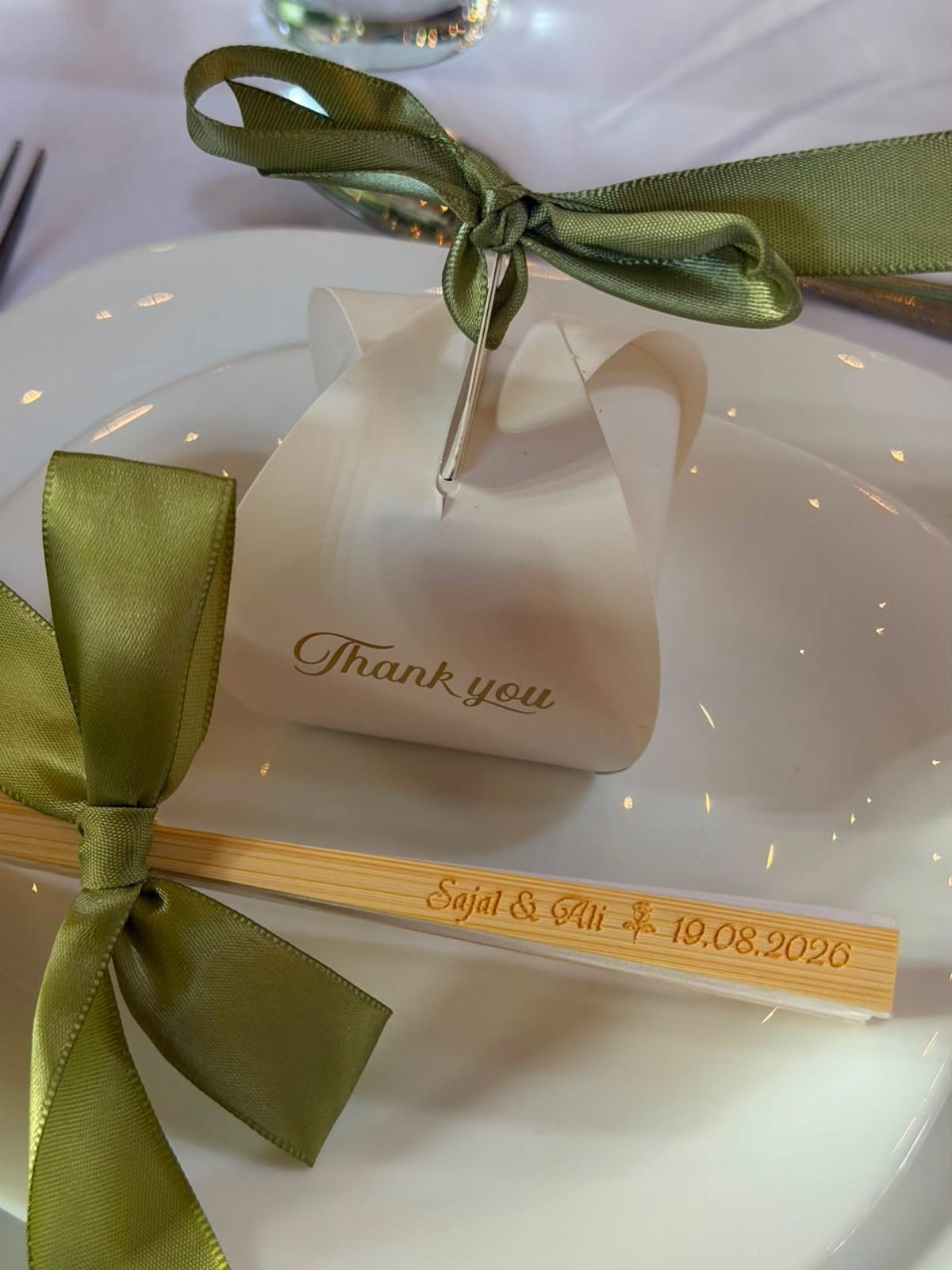 Personalised thank-you favour box and engraved keepsake chopsticks tied with sage ribbon on a place setting