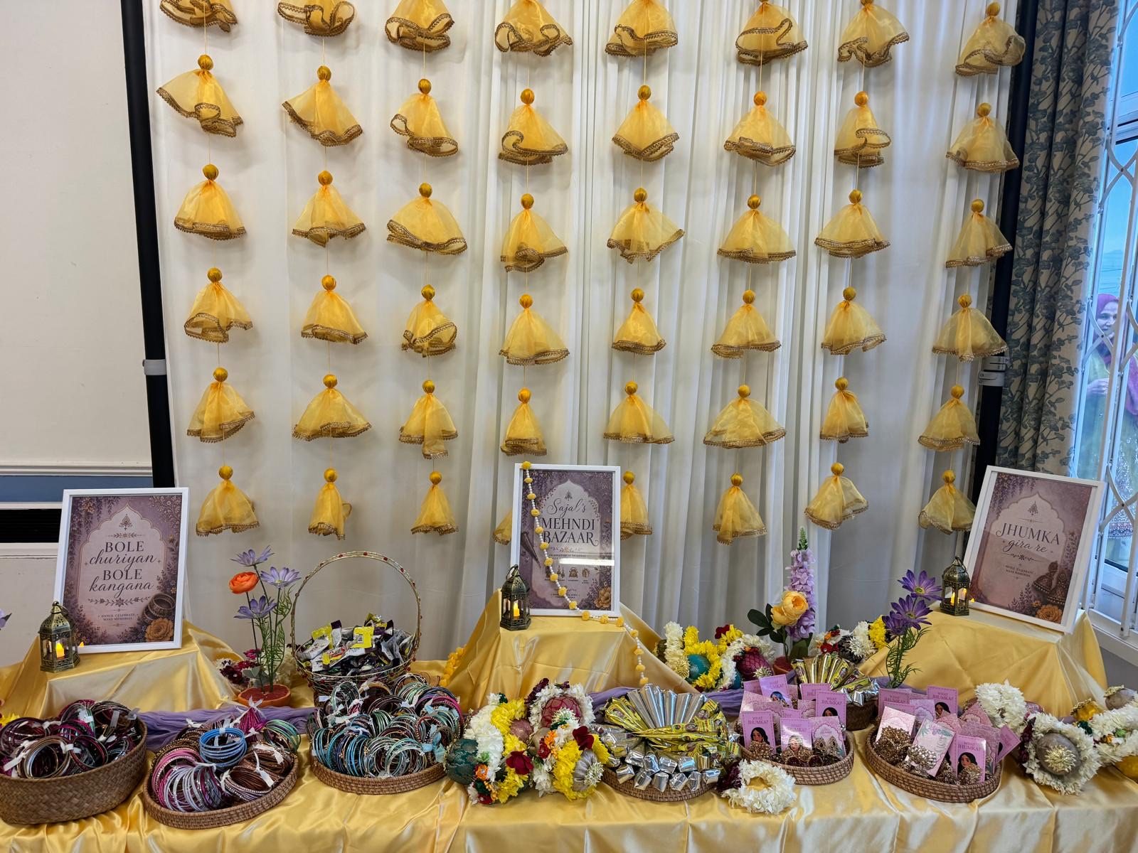 Close view of the Mehndi Bazaar with baskets of bangles, jhumkas and favour signs on a golden cloth
