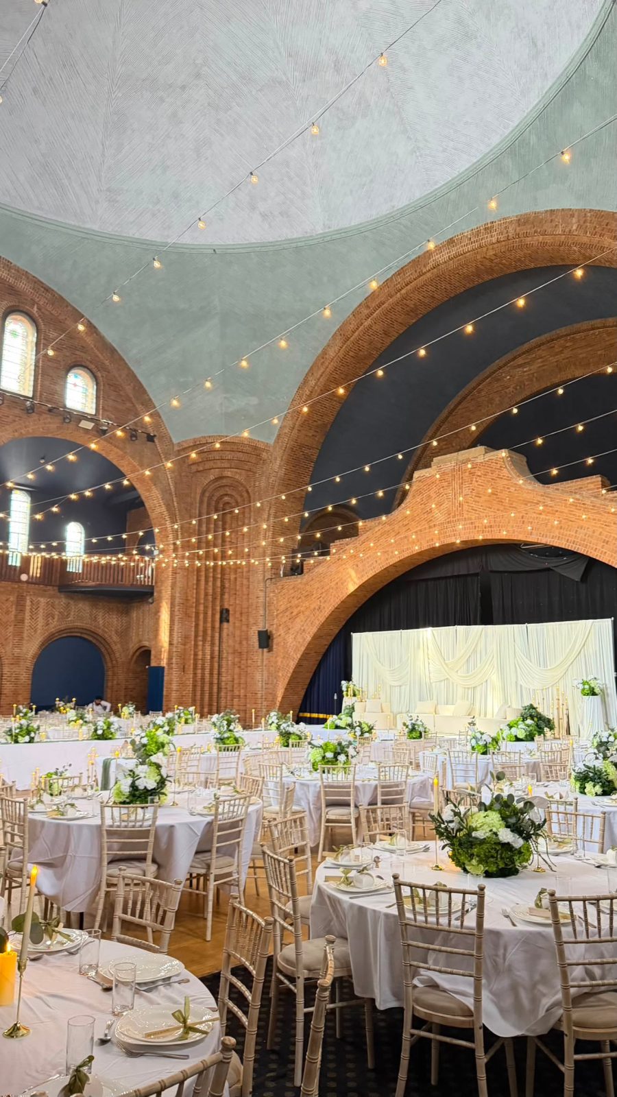 Candlelit reception tables set beneath soaring illuminated brick archways
